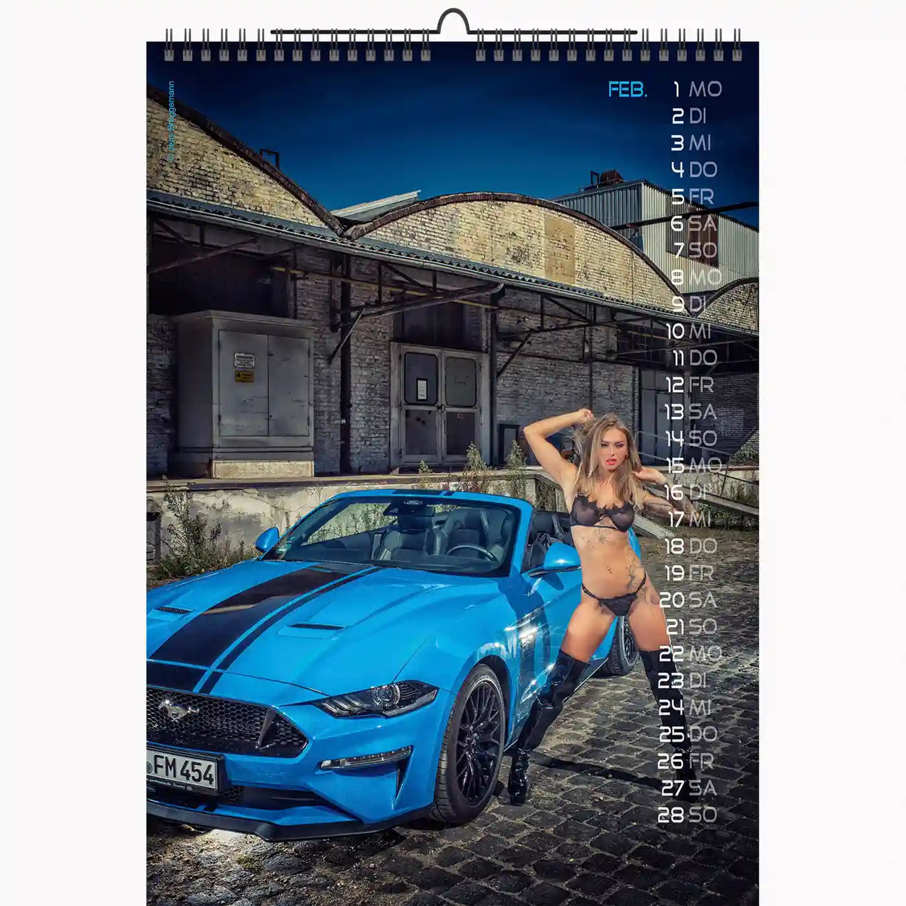 Calendar with a blue car and a person in lingerie on a cobblestone street.