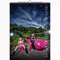 Calendar with two women in pink outfits and a pink car on a scenic road.