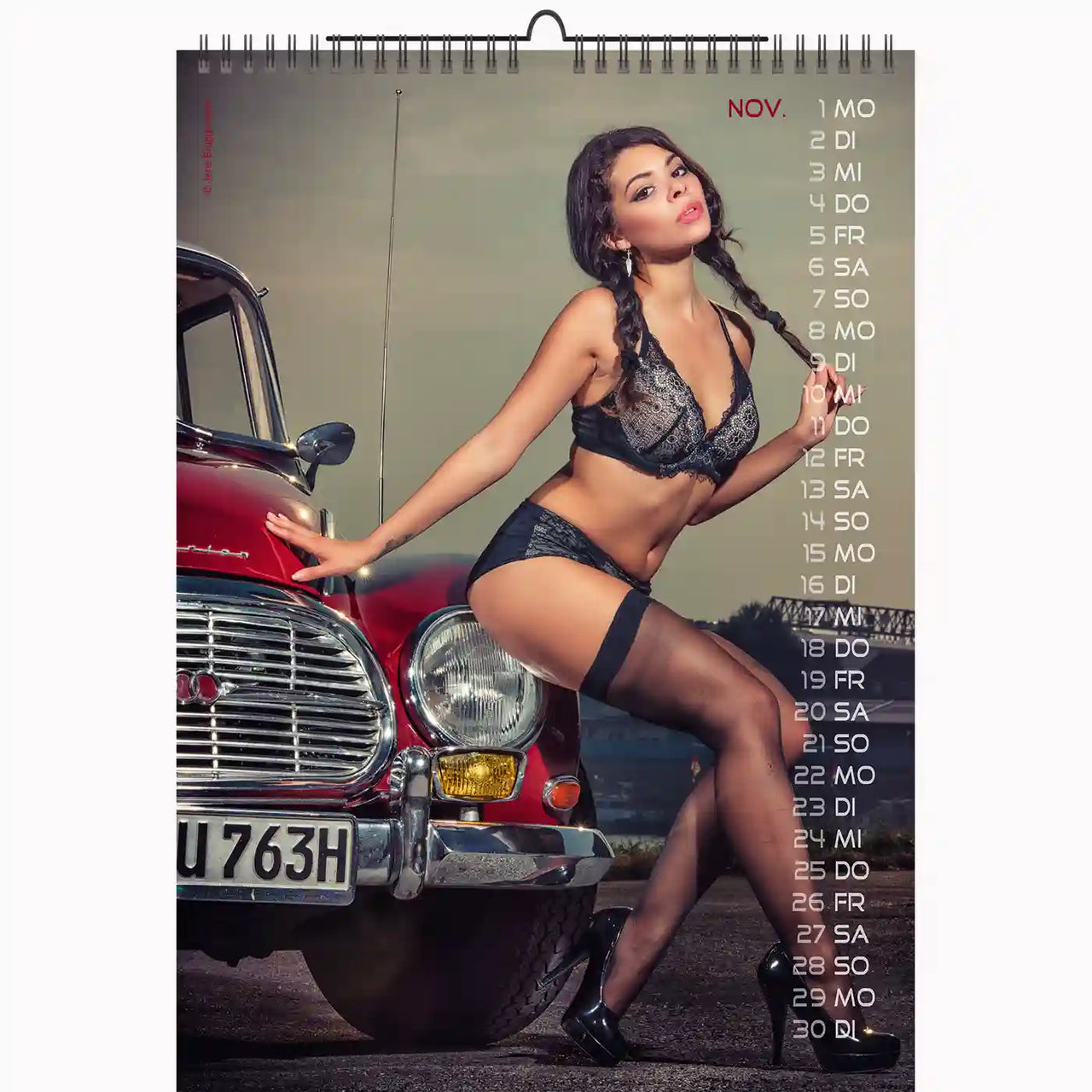 Calendar with a model posing next to a red car, featuring a scenic background.