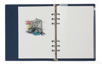 Open notebook with a colorful illustration of a bridge and buildings on the left page, on a white background.