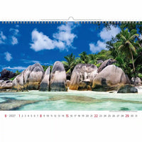 Kalender met een tropisch strandtafereel met rotsen, palmbomen en helderblauw water.