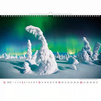 Kalender met een winterlandschap met besneeuwde bomen en het noorderlicht.