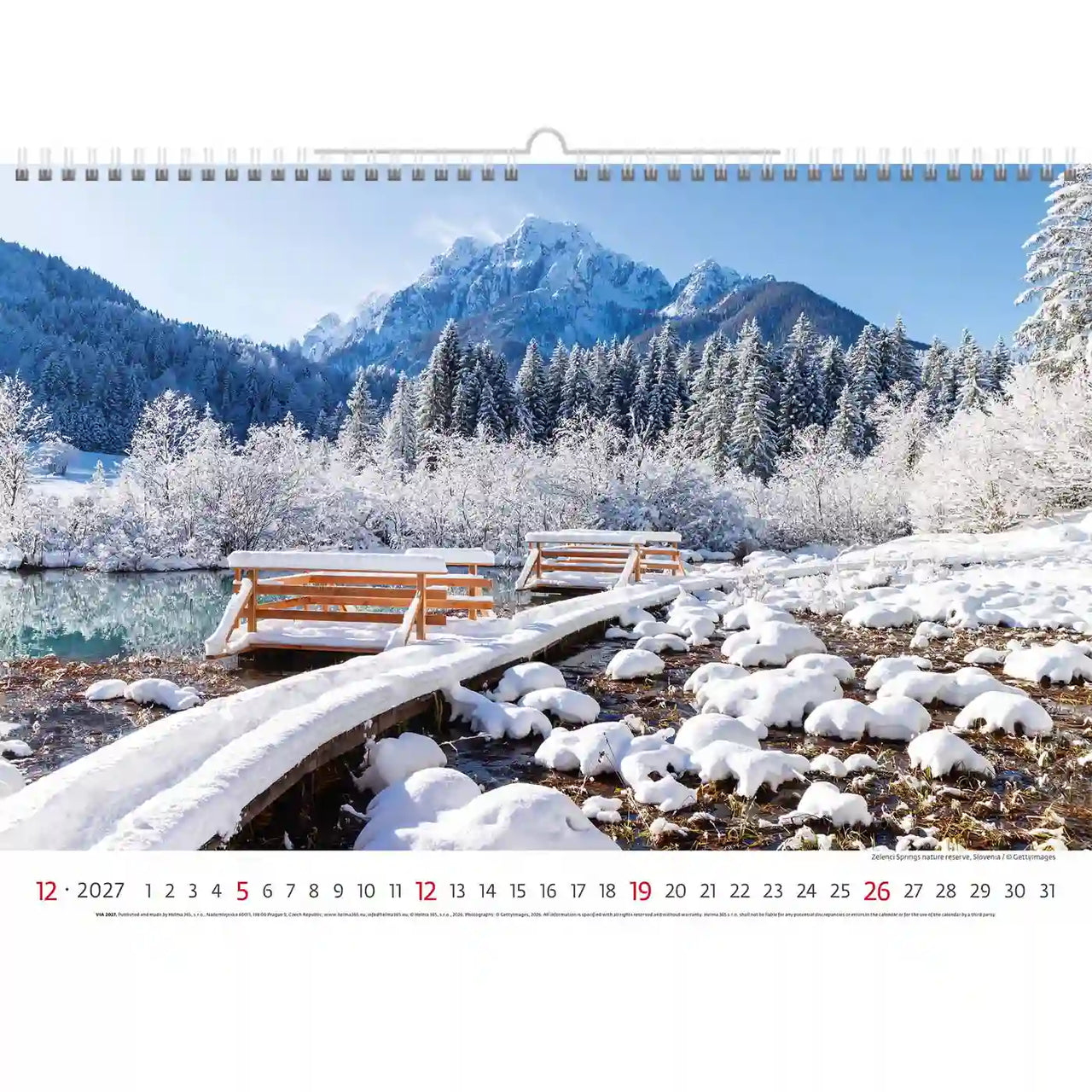 Winterlandschap met besneeuwde bergen en bomen, met een houten bankje op een kalender.