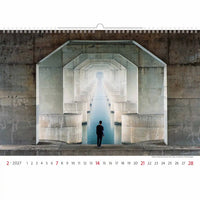 Kalender met een persoon die voor een glazen wand staat waar licht doorheen schijnt, tegen een betonnen muur.