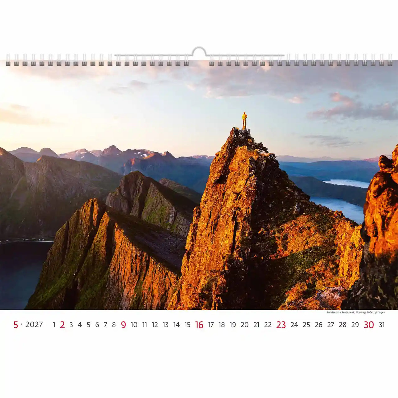 Kalender met een berglandschap met daarop een standbeeld, tegen een zonsonderganghemel.