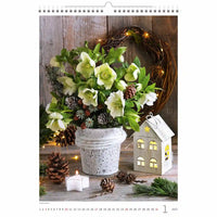Decoratieve kalenderpagina met een potplant, kaarsen en een huisvormige lantaarn op een houten oppervlak.