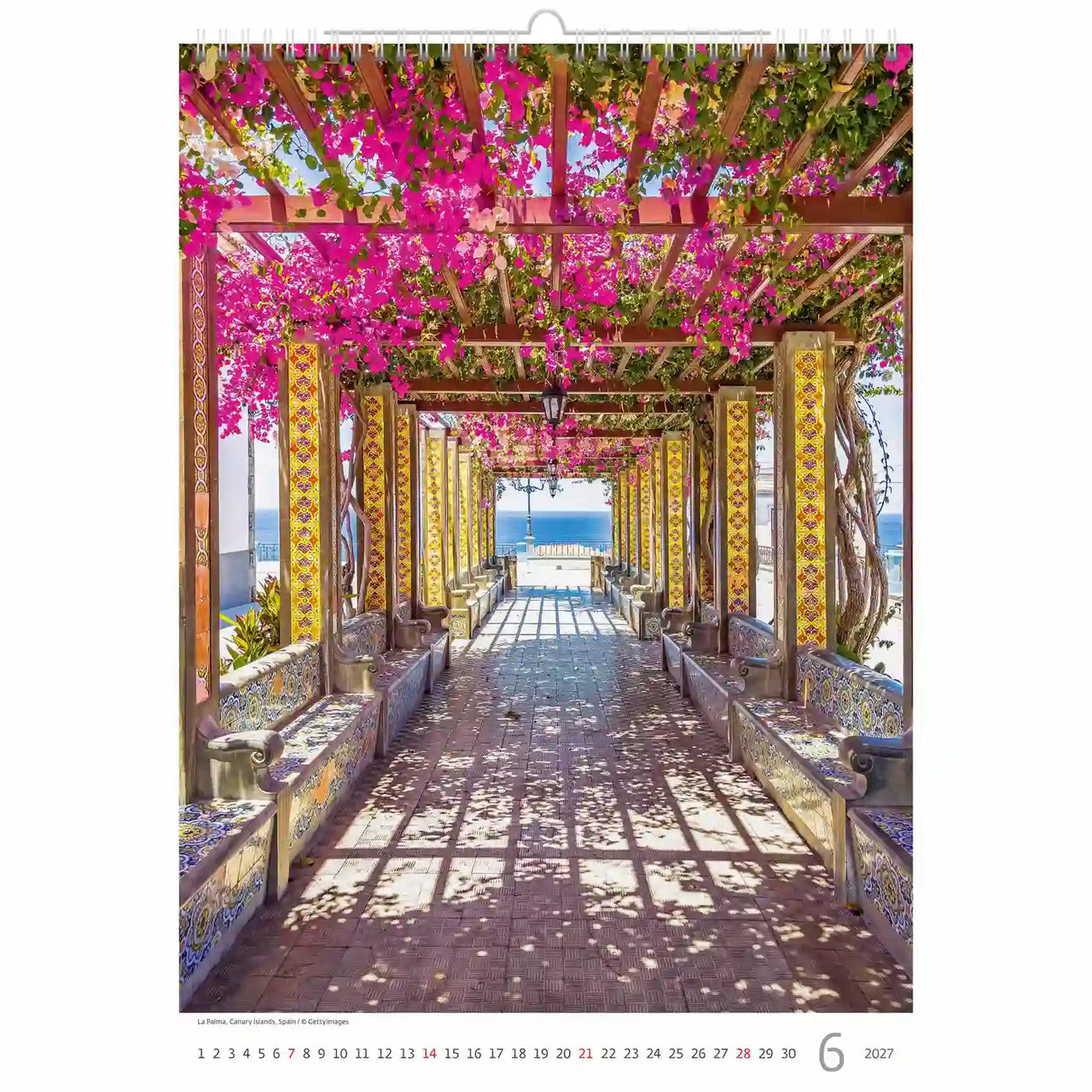 Bloemenboog met roze bloemen die leiden naar een schilderachtig uitzicht, waarschijnlijk afkomstig van een kalender.