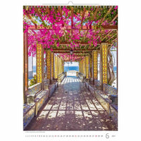 Bloemenboog met roze bloemen die leiden naar een schilderachtig uitzicht, waarschijnlijk afkomstig van een kalender.