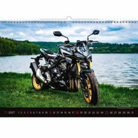 Motor op een grasveld met een schilderachtige achtergrond, met een kalender.