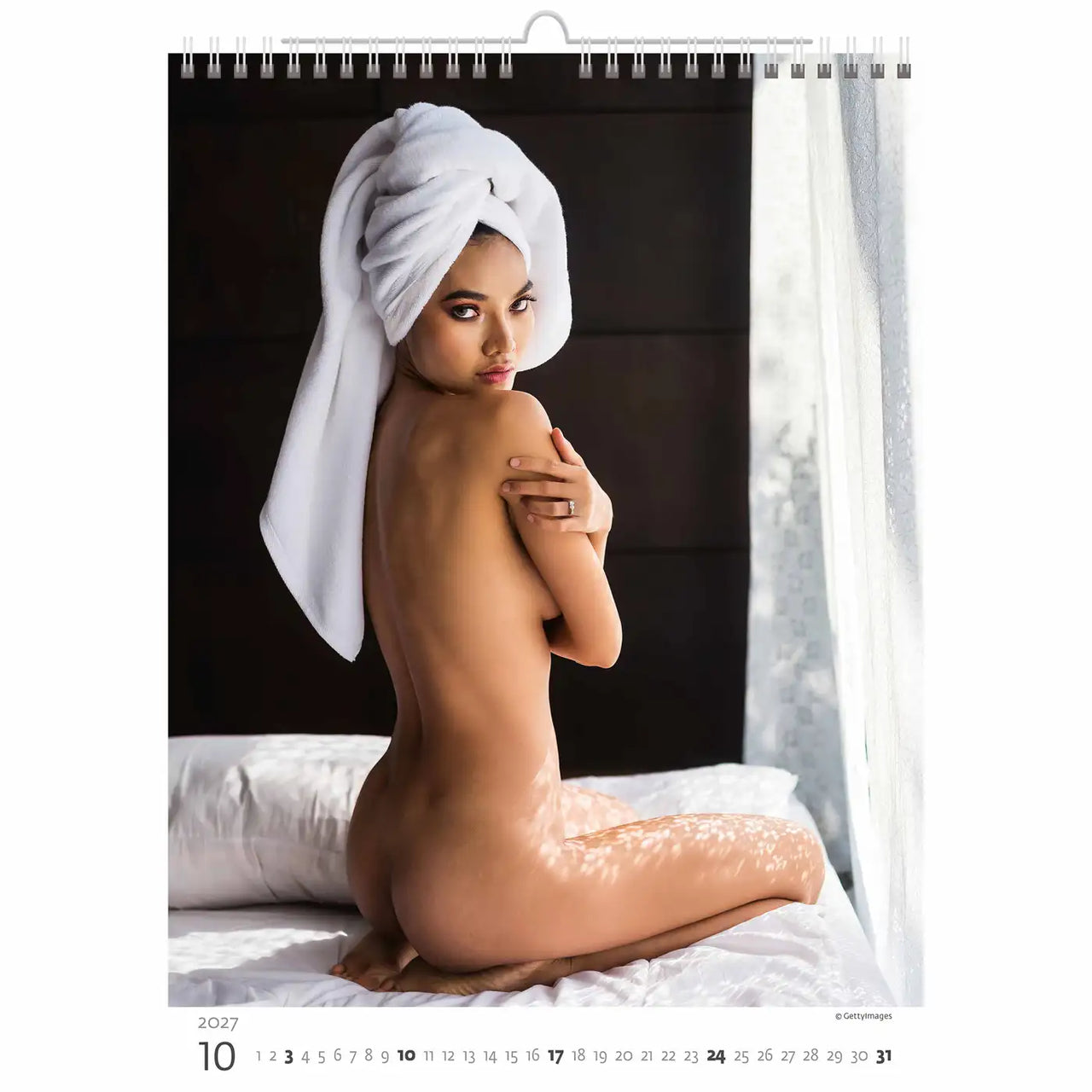 Naked person with a white towel on their head, sitting on a bed, calendar page.
