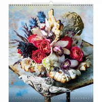 Arrangement floral avec des roses rouges et d'autres fleurs sur une surface décorative, représentant le mois d'août.