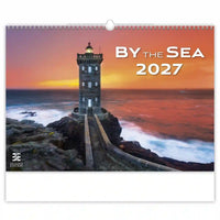 Kalenderomslag met een vuurtoren op rotsen en zonsondergang boven de zee, getiteld 'By the Sea 2027'.