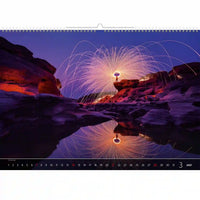 Kalender met een schilderachtig aanzicht van een persoon die een lichtshow creëert in een rotsachtig landschap.
