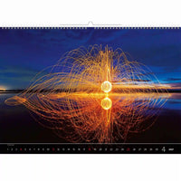 Kalender met een lichtkunstdisplay op het water bij nacht, met een blauwe lucht en oranje lichten.