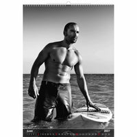 Zwart-wit kalenderpagina met een man met een surfplank in de oceaan.