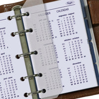 Calendar pages of a planner with metal rings on a wooden surface